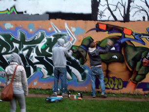 Graffiti artists touching up their portrait of Donatello, the Teenage Mutant Ninja Turtle